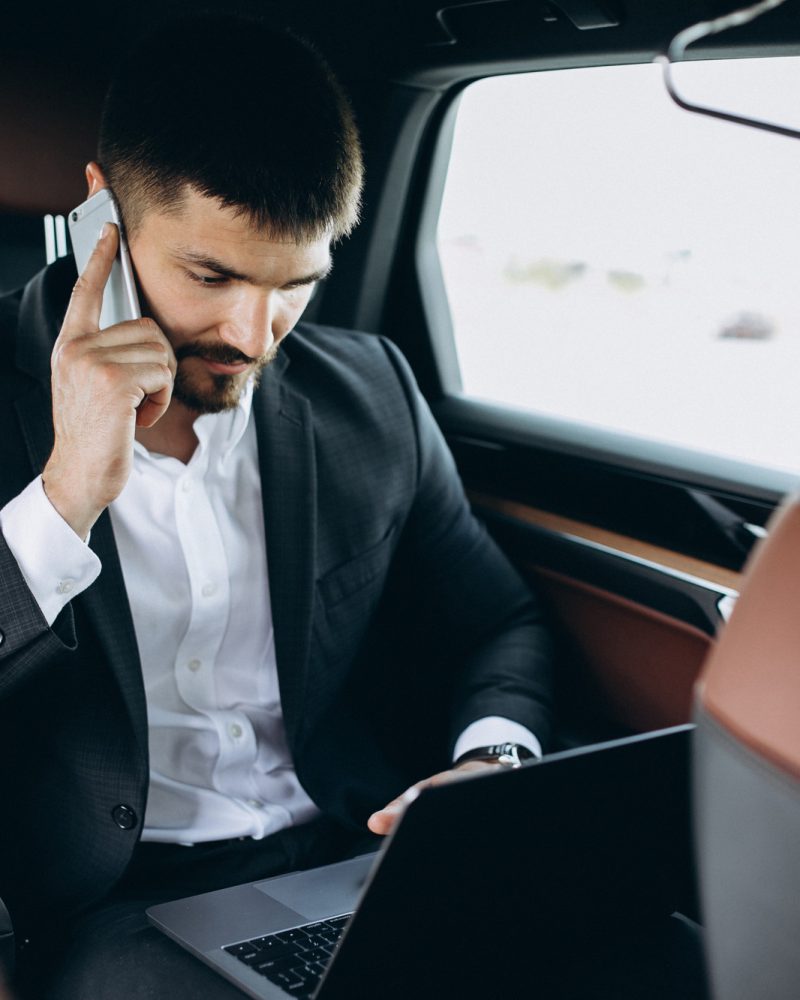 Handsome business man working on a computer in car